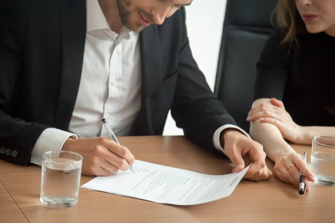 Couple signing legal documents, representing pre and postnuptial agreements with family law guidance in California.