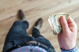 Can Family Law Courts Assign Income for Child or Spousal Support? This picture features a person looking down while holding money in their right hand.